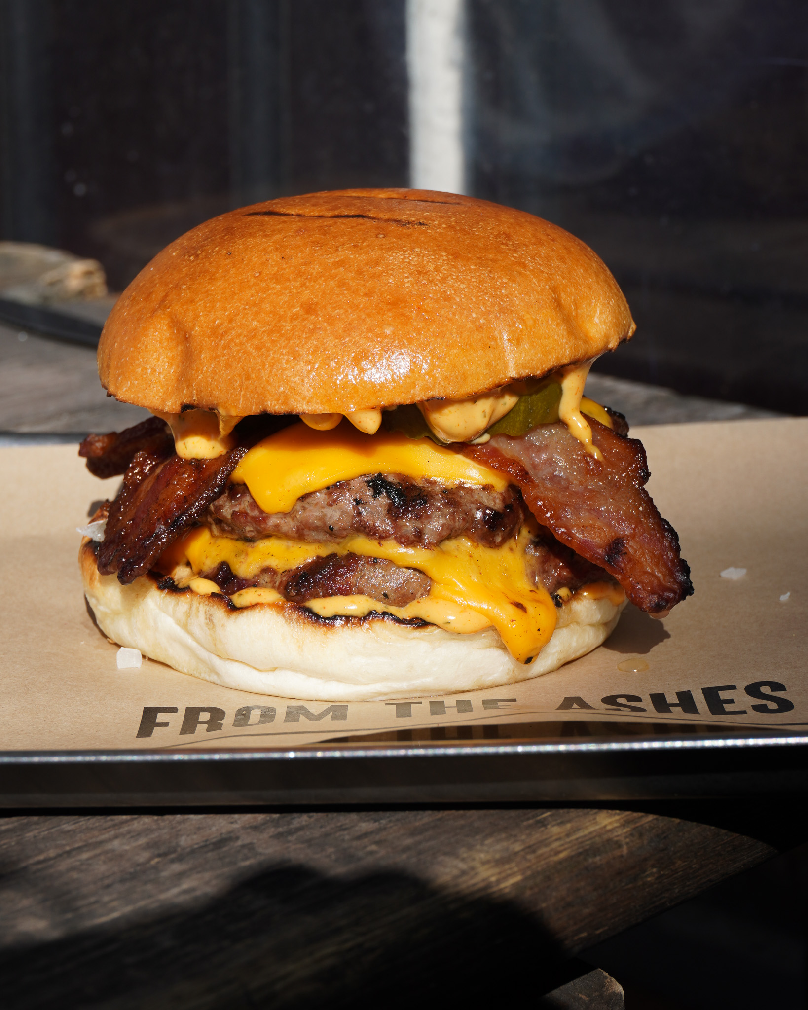 An image of a smash burger with bacon in the sun
