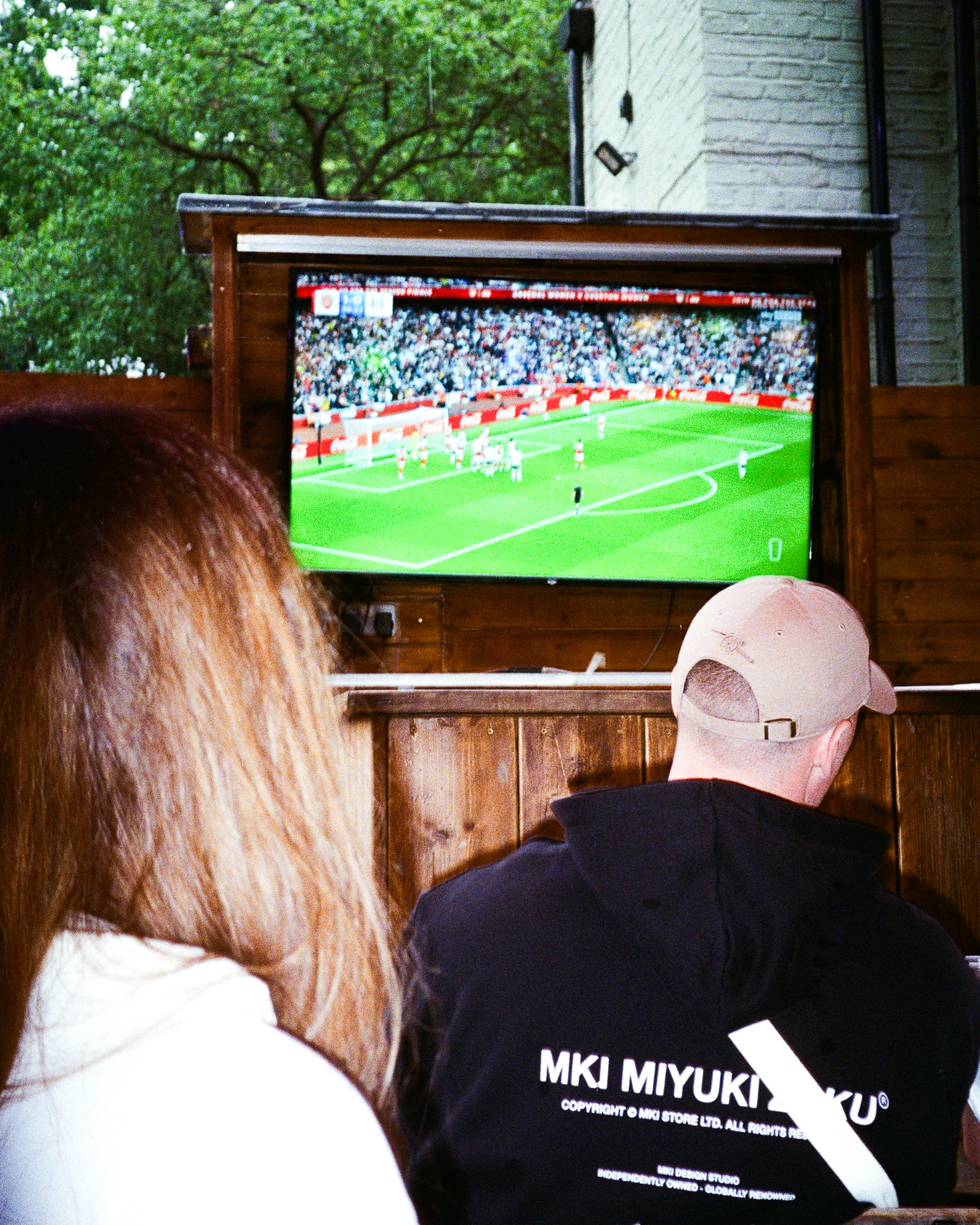 Photo of a TV on deck one at pub on the park with two people watching.